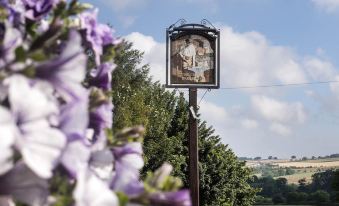 a signpost with a woman and a child on it , surrounded by flowers and trees at The Cook and Barker Inn