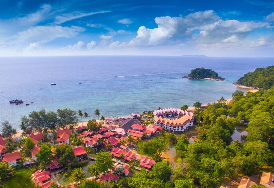 an aerial view of a beach resort with a large circular building and a small island in the distance at Paya Beach Spa & Dive Resort