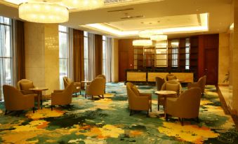 a modern hotel lobby with green carpet , wooden furniture , and a chandelier , decorated with large windows and bookshelves at Sunshine Hotel