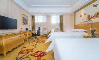 a hotel room with two beds , a desk , and a chair , all set against a white wall at Vienna Hotel