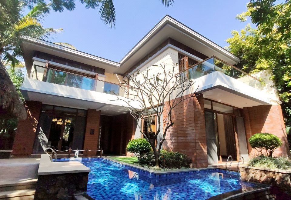 a large , modern house with a swimming pool in the backyard , surrounded by lush greenery at Sanya Haitang Bay Island Villa (International Duty Free City Branch)