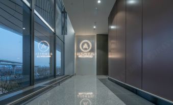 There is a building entrance with large windows and an illuminated sign on the wall at Aerotel Beijing