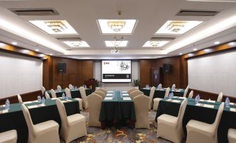 a large room is arranged with tables and chairs, facing the front, for an event at Fortune Hotel