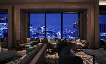 a luxurious hotel lobby with a large window overlooking the city , showcasing a bustling nightlife scene at The Royal Park Hotel Iconic Osaka Midosuji