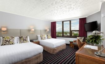 a hotel room with two beds , a window , and a desk , all decorated in white and brown colors at Rydges Southbank Townsville, an EVT hotel