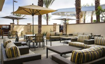 an outdoor patio area with several lounge chairs , tables , and umbrellas , creating a relaxing atmosphere at Fairfield Inn & Suites by Marriott Tustin Orange County
