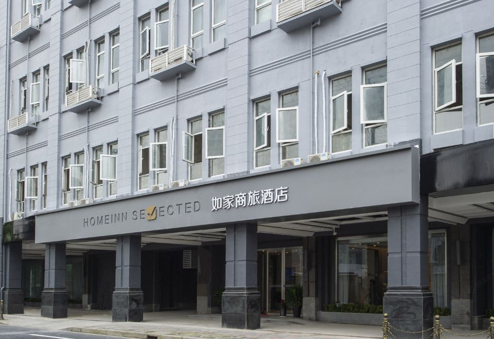 The front entrance of a modern hotel in an urban setting with large architectural features at Home Inn (Shanghai North Bund Dalian Road Subway Station)