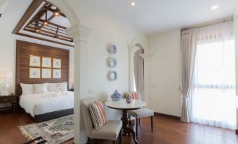 a modern , minimalist bedroom with white walls and wooden floors , featuring a large bed , a dining table , and a couch at Content Villa Chiangmai