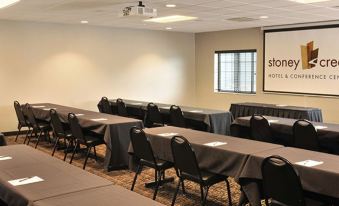 a conference room with multiple rows of tables and chairs , a window , and a sign on the wall at Boarders Inn & Suites by Cobblestone Hotels – Waukon