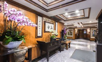 a well - decorated hotel lobby with wooden walls , oriental decorations , and a large vase of flowers at Han She Business Hotel