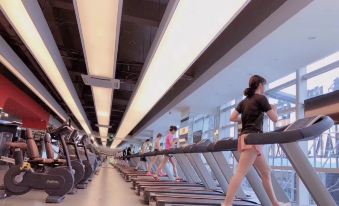 People are exercising on treadmills and other exercise machines in a spacious room at YiWu Zhonglian Kaixin Hotel
