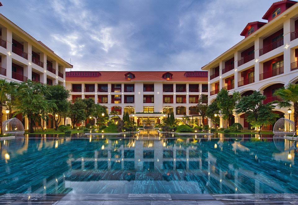 a large hotel with a pool and multiple buildings is shown during the evening hours at Senna Hue Hotel