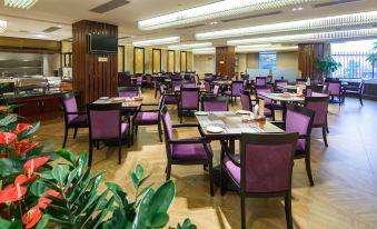 a large dining room with purple chairs and tables , along with potted plants on the floor at City Hotel