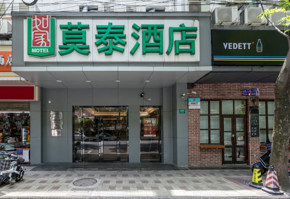 The front entrance of a restaurant is adorned with a sign above it, and the building showcases an oriental style at Motel Hotel (Shanghai Changping Road Metro Station)