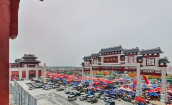a bustling outdoor market with numerous cars parked in the lot and umbrellas set up for customers to enjoy at Spring Hotel