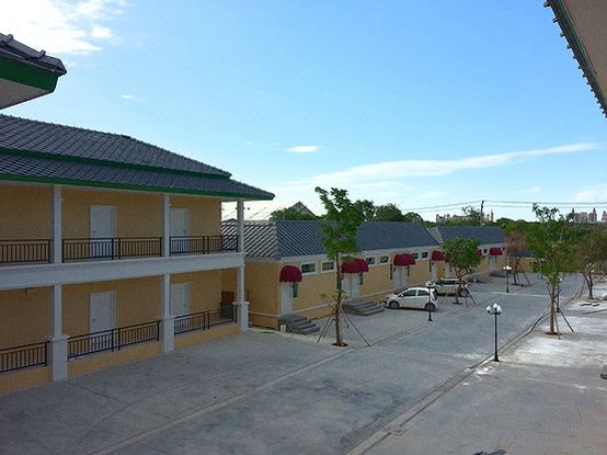 a sunny day view of a building with red awnings and trees in the foreground at Pudis Ville