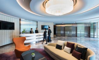 a hotel lobby with a reception desk , couches , and a round ceiling fixture above the couch at Novotel Taipei Taoyuan International Airport