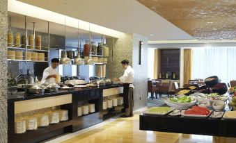 A restaurant with large windows and tables in the middle, alongside an open kitchen at Courtyard by Marriott Shanghai Central