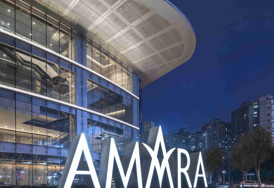 At night, a hotel entrance is illuminated by its sign, with other buildings visible in the background at Amara Signature Shanghai