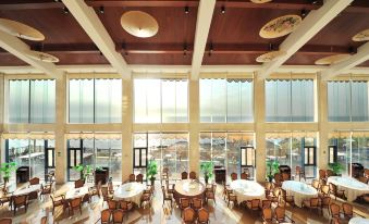 The restaurant features large windows, tables in the middle, and an arched ceiling at Beidaihe Bei Hua Yuan Sea View Hotel (Beidaihe Biluo Tower)