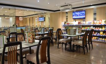a dining area in a restaurant with tables and chairs , as well as a television mounted on the wall at Executive Hotel