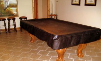 a brown billiards table in a room with wooden furniture and a tiled floor , surrounded by paintings and other decorative items at Mountain Cove Farms Resort