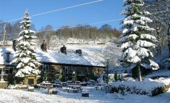 a snow - covered ski resort with a cabin nestled in the trees , surrounded by snow - covered mountains at The Lamb Inn