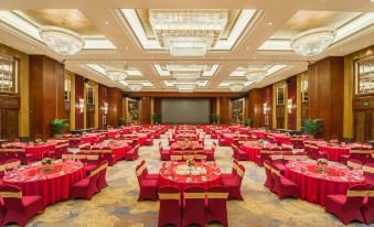 a large banquet hall with multiple red tables and chairs arranged for a formal event at Royal Garden Hotel