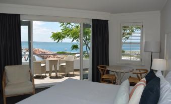 a bedroom with a large window overlooking the ocean and a table with chairs on it at Anchorage Port Stephens