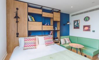 A bedroom with white walls and wood paneling features an open space next to the bed at Campanile Shanghai Huaihai Hotel