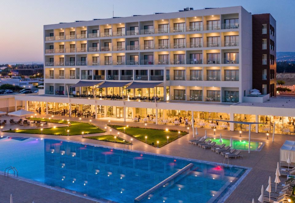 a large hotel with a swimming pool surrounded by grass and people in the pool area at The Ivi Mare - Designed for Adults by Louis Hotels
