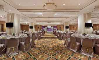 The ballroom is set up with tables and chairs in the center for events or wedding receptions at Harbour Plaza Resort City