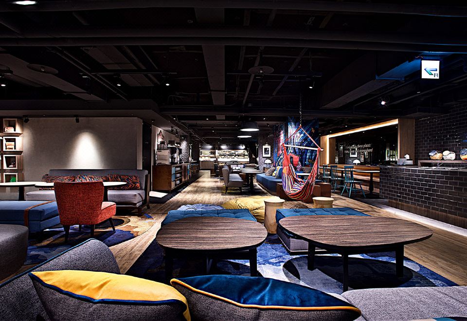 a modern living room with multiple couches , chairs , and tables , as well as a hammock hanging from the ceiling at Just Sleep Ximending