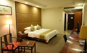 a large bed with a wooden headboard is in the middle of a room with a table and chairs at Spring Hotel