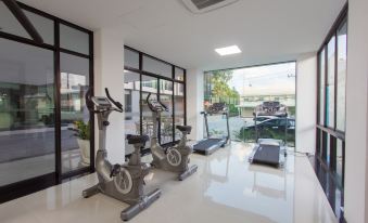 a well - equipped gym with various exercise equipment , including treadmills and stationary bikes , near large windows that offer views of the outdoors at Siva Royal Hotel