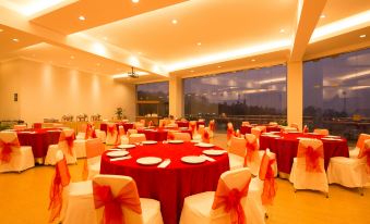 a large room with round tables covered in red tablecloths and white chairs arranged around them at Hotel Cianjur Cipanas