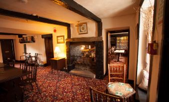 a cozy living room with a fireplace , wooden furniture , and a carpeted floor , creating a warm and inviting atmosphere at The Punchbowl Inn