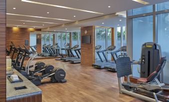 a modern gym with large windows , wooden flooring , and various exercise equipment including treadmills , stationary bikes , and weights at Grand Hyatt Manila