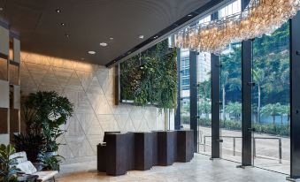 The lobby features a large plant wall and illuminated chandeliers hanging above at The Emperor Hotel