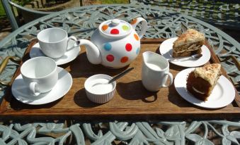 a wooden tray filled with a variety of tea and coffee items , including cups , saucers , and a teapot at Moor Court Farm