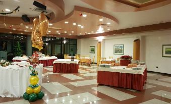 a large room with tables and chairs , a gold balloon , and a window in the background at Hotel Astoria