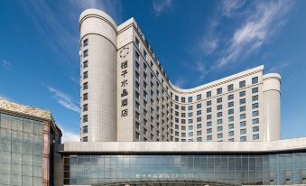The large glass windows of a building in an urban setting offer clear views of both the front and side of the building on a sunny day at Crystal Orange Hotel（Shanghai Hongqiao Gubei Road）
