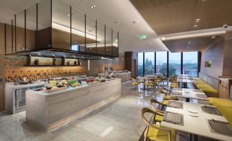 The restaurant features large windows, tables in the middle, and an open concept kitchen at Hilton Garden Inn Shanghai Hongqiao NECC