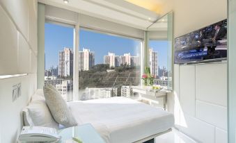 The bedroom features large windows and a balcony that overlook the city at night at iclub To Kwa Wan Hotel