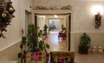 a room with two chairs and a couch , decorated with christmas ornaments and plants , is seen from the entrance at Breffni Arms Hotel