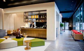 a modern , minimalist interior design with green and white accents , wooden furniture , and a bartender at work at Glam Milano