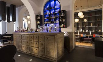 a bar with a wooden counter and shelves of bottles behind it , along with several lamps hanging from the ceiling at Rome Times Hotel