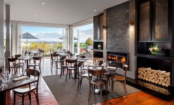 a large dining room with wooden tables and chairs , a fireplace , and a view of the ocean at Hilton Lake Taupo