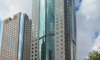 A large building with glass windows stands in the middle, with a blue sky as its backdrop at Holiday Inn Shanghai Pudong