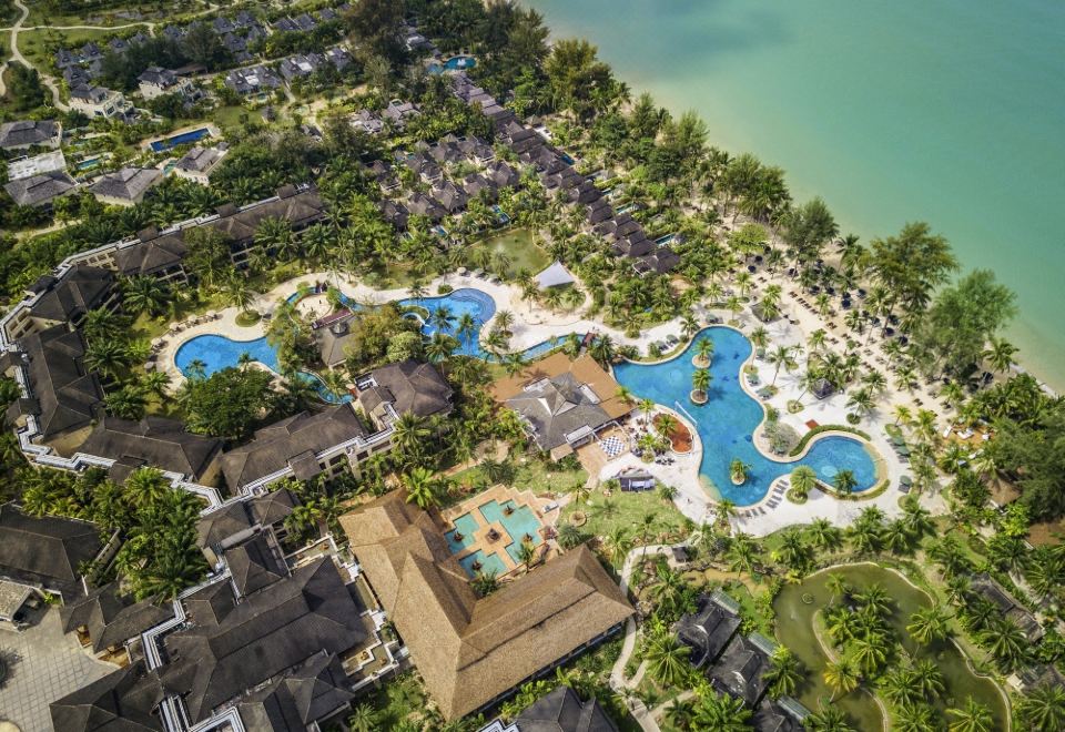 aerial view of a resort with multiple pools , water slides , and palm trees surrounding a beach at Robinson Khao Lak